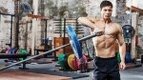 Muscular man performing a full body landmine workout with his shoulders with a landmine shoulder pressit to Improve Mobility and Boost Strength