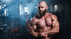 A bald bodybuilder showing his muscular physique after training with delt exercises