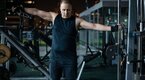 Average fitness goer performing a cable lateral raise to build his deltoids and shoulders