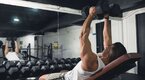 Fit man working out in the gym using Incline Bench Lateral Raise exercise to build his delts